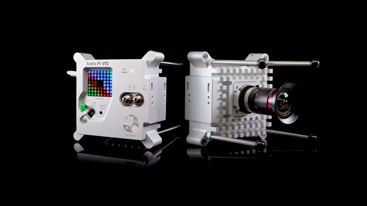 The Astro Pi kit, the image shows the front and back of the kit. The front of the device has a large camera lens. On the rear of the device is a 8x8 led screen and several more controls.